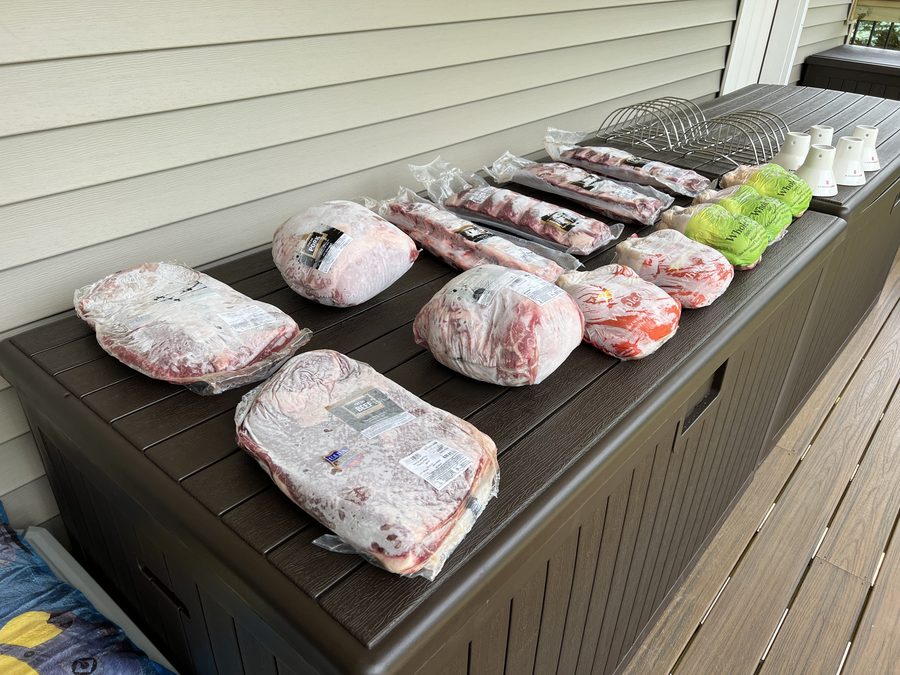 An assortment of meats cooking on the grill at a Tompkins family gathering